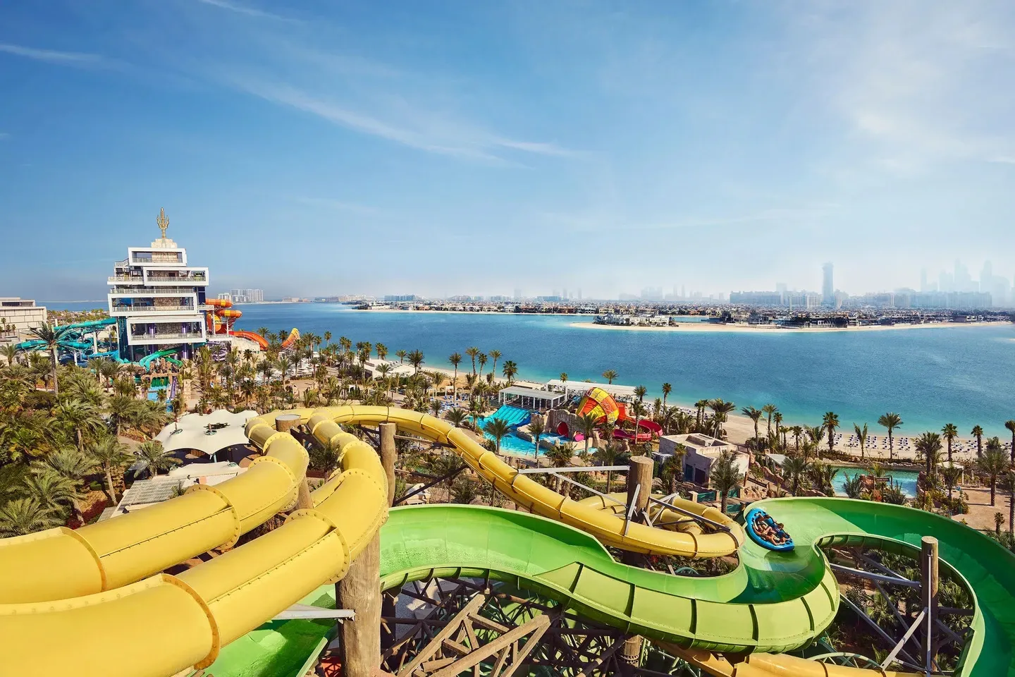 Atlantis Aquaventure Waterpark in Dubai with thrilling water slides, palm trees, beach view, city skyline, and turquoise waters.