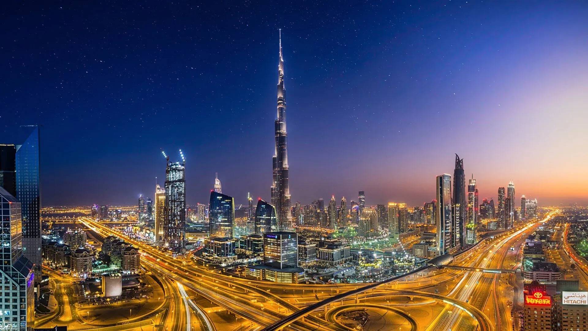Dubai Skyline at Night with Burj Khalifa and Illuminated Skyscrapers Over Busy Highways