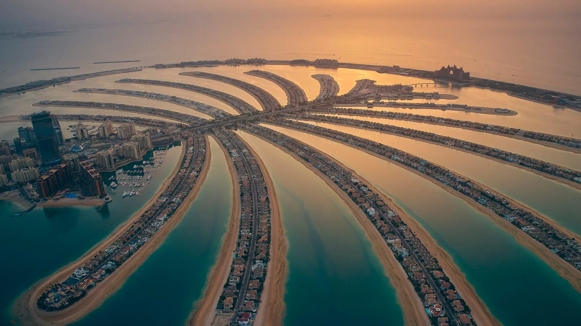 Aerial view of Palm Jumeirah in Dubai at sunset, with the palm-shaped island, Atlantis Resort, luxury villas, and turquoise waters.