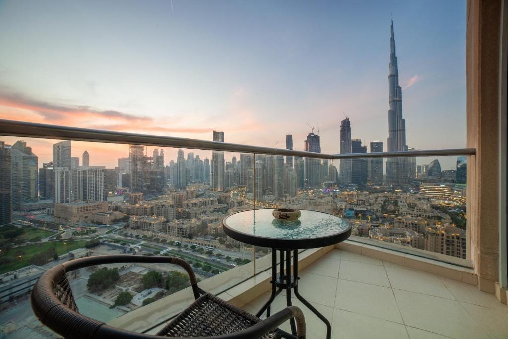 Balcony view of Downtown Dubai skyline and Burj Khalifa at sunset from a high-rise apartment.