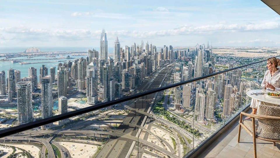 Stunning Dubai Marina skyline view from a high-rise Sobha Central balcony, with a woman enjoying breakfast outdoors.