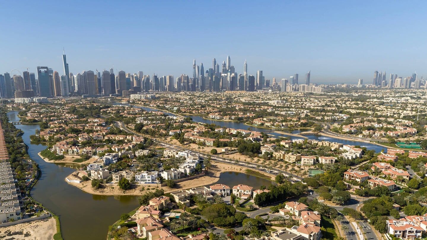 Aerial view of Jumeirah Islands in Dubai with luxury villas, lakes, and the Marina skyline in the background.