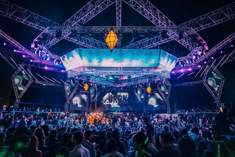 White Dubai nightclub URBN party with massive crowd, futuristic stage, and high-energy nightlife under open skies.