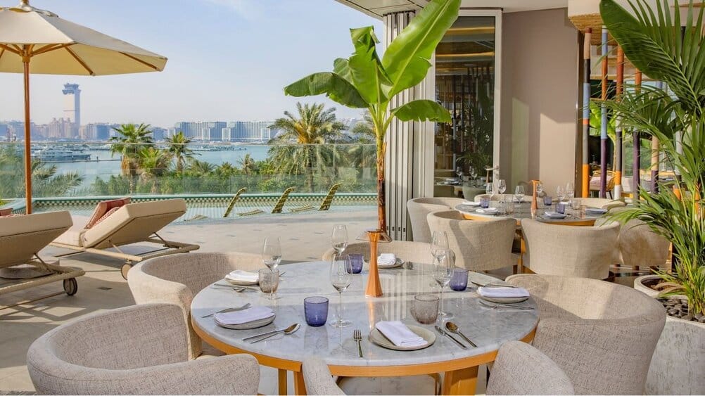 Elegant beachfront restaurant terrace in Dubai with sea views, palm trees, and stylish outdoor seating