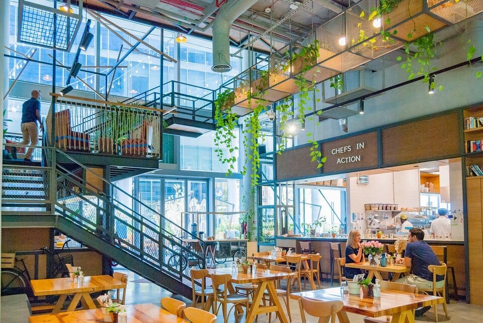 Bright modern interior of One Life Kitchen & Café Dubai with open kitchen, plants, and wooden dining tables