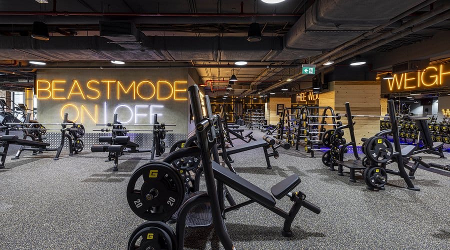 GymNation Dubai weightlifting area with modern machines, free weights, and neon “Beastmode On” sign in 2025.