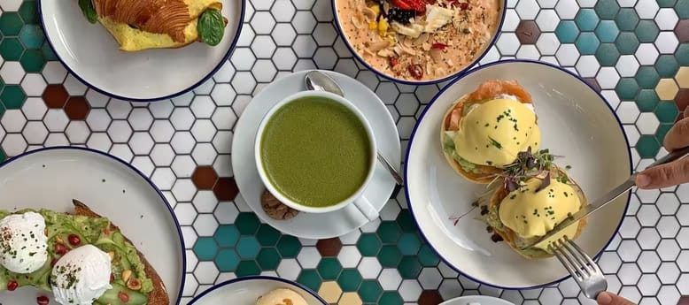 Healthy breakfast with eggs benedict, avocado toast, croissant, matcha latte and granola bowl at Dubai cafe