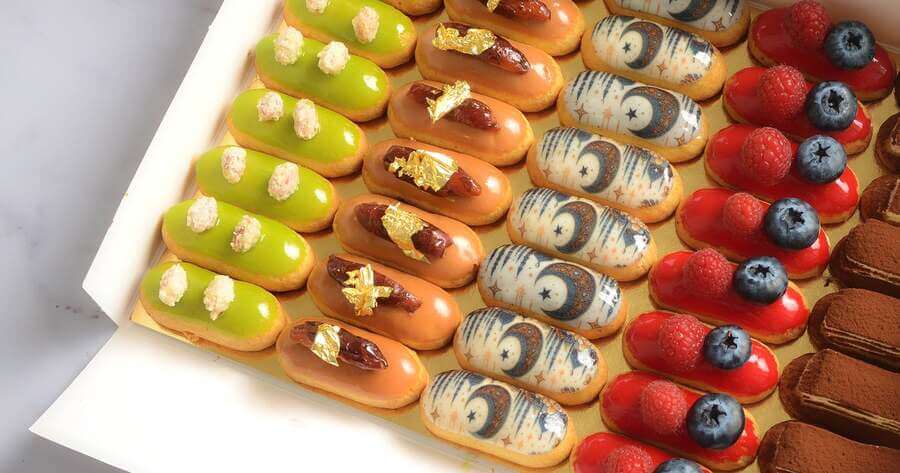 L’Éclair de Génie Dubai gourmet assorted éclairs topped with gold leaf, fresh berries, and artistic glaze