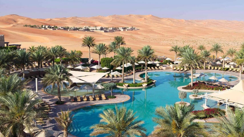 Luxury resort in Liwa Oasis with palm-lined pool, set against the vast dunes of the Empty Quarter in the UAE desert.