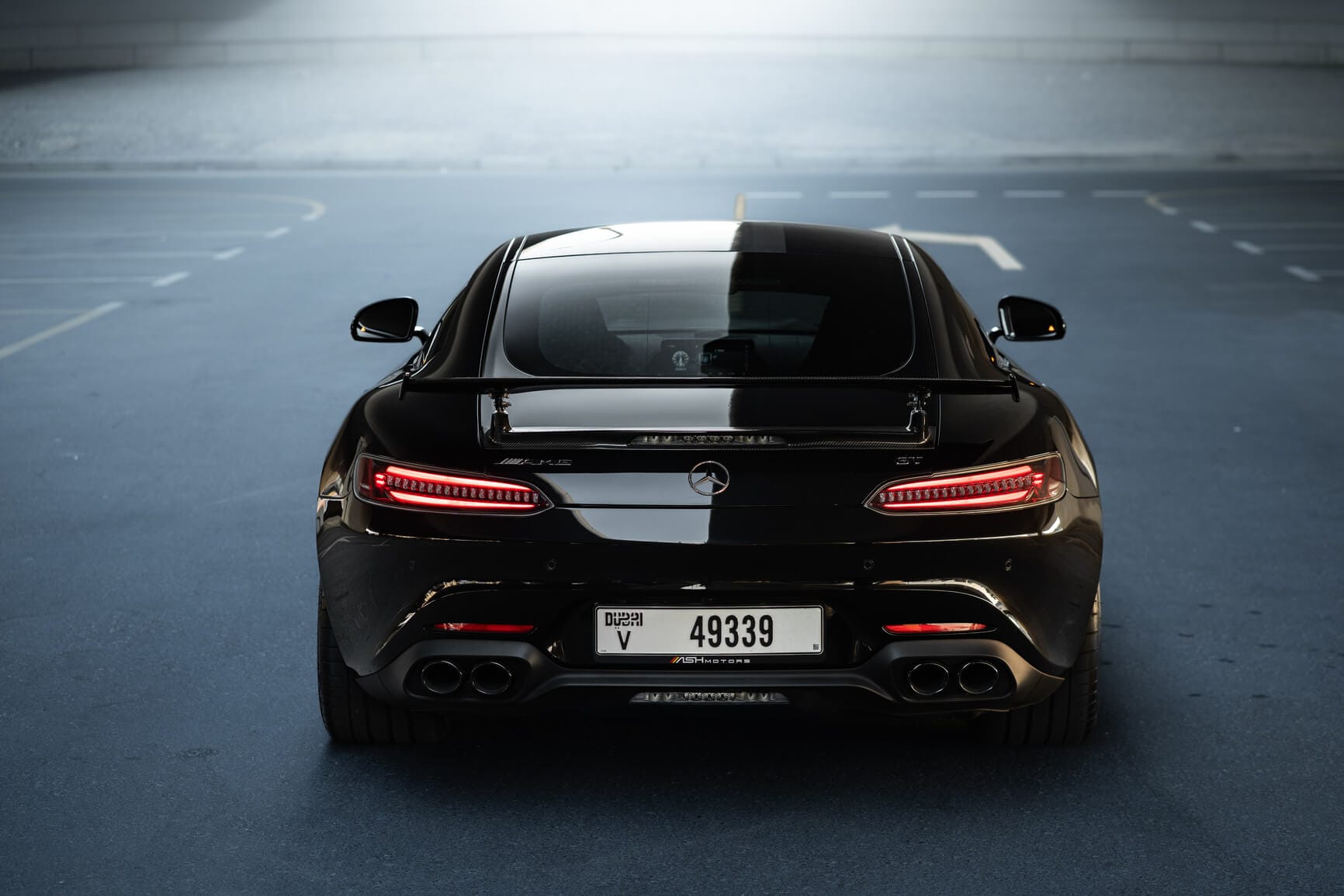 Rear view of black Mercedes-AMG GT Night Edition with carbon spoiler and quad exhaust, luxury rental car in Dubai