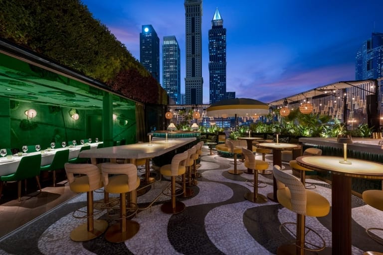 Amazonico Dubai rooftop bar with modern seating, lush decor, and city skyline views at dusk