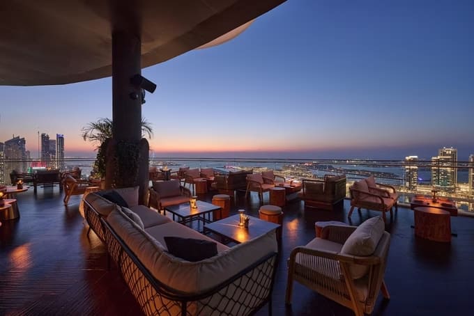 Attiko rooftop lounge at W Dubai Mina Seyahi with cozy seating and panoramic sunset views over the city and sea