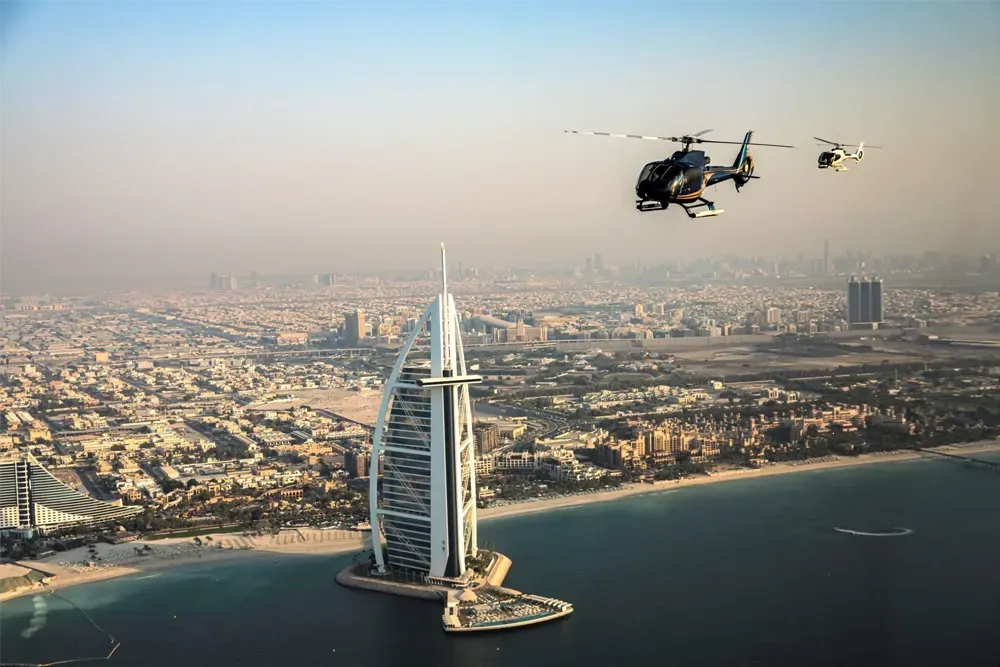 Helicopters flying over Burj Al Arab with panoramic view of Dubai skyline and coastline in the background