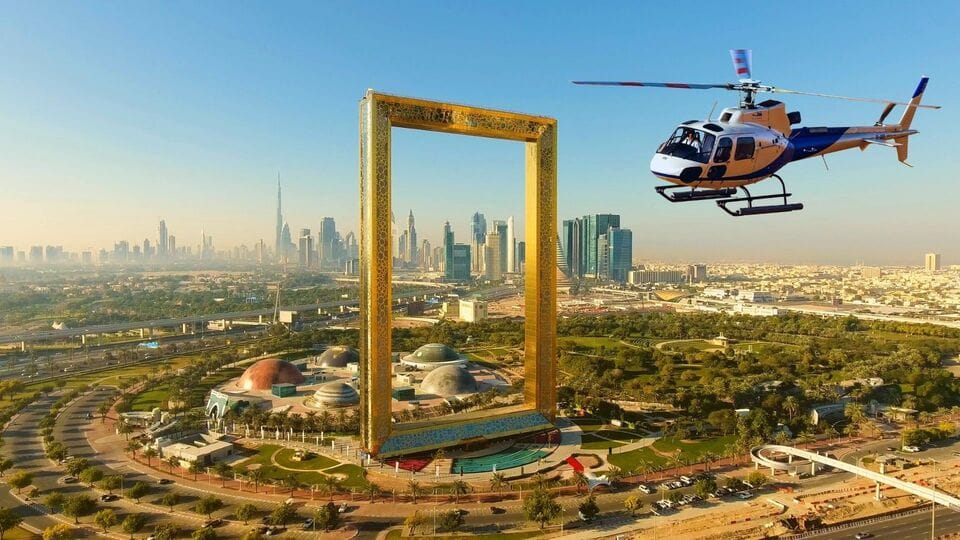 Helicopter flying near Dubai Frame with city skyline and Burj Khalifa visible in the background during golden hour