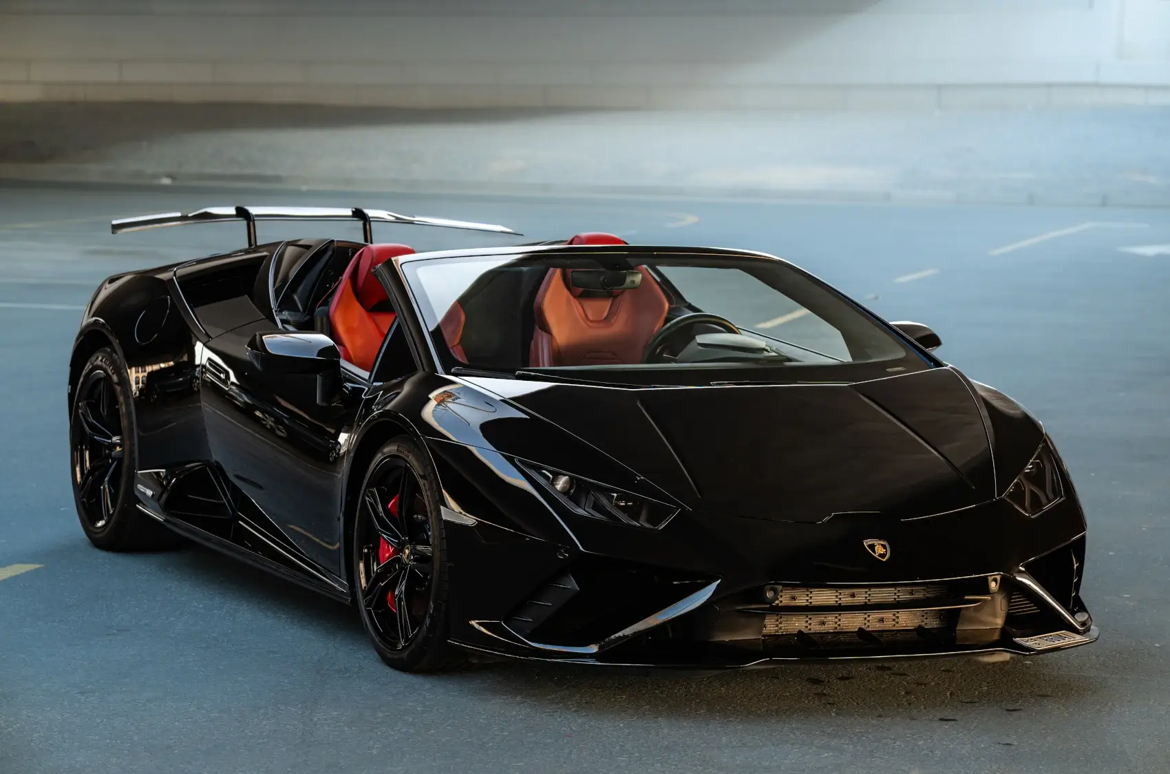 Front angle view of black Lamborghini Huracán EVO Spyder with red interior for rent in Dubai