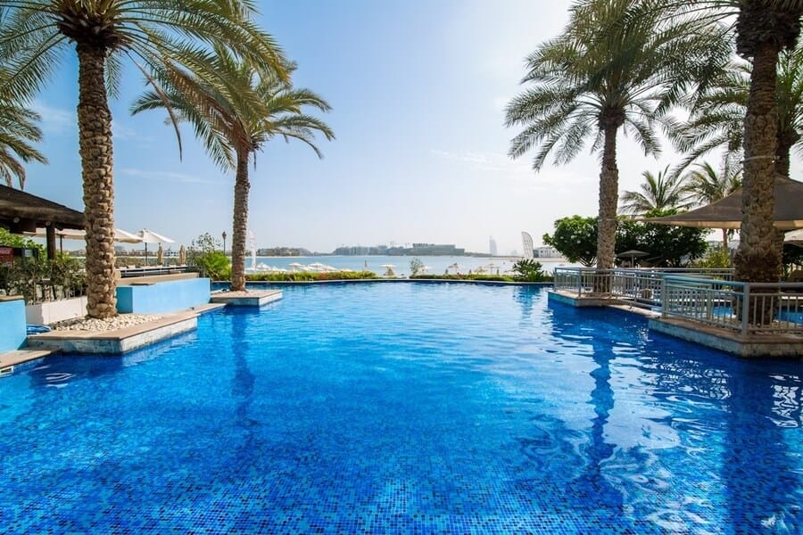 Infinity pool at Riva Beach Club with a view of Palm Jumeirah and Burj Al Arab in the distance