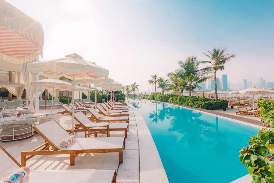 Chic poolside loungers and umbrellas at The 305 Beach Club with views of Palm Jumeirah skyline in Dubai