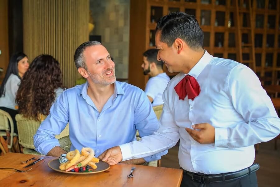 Smiling diner tipping waiter at Dubai restaurant, showcasing local dining and tipping etiquette.