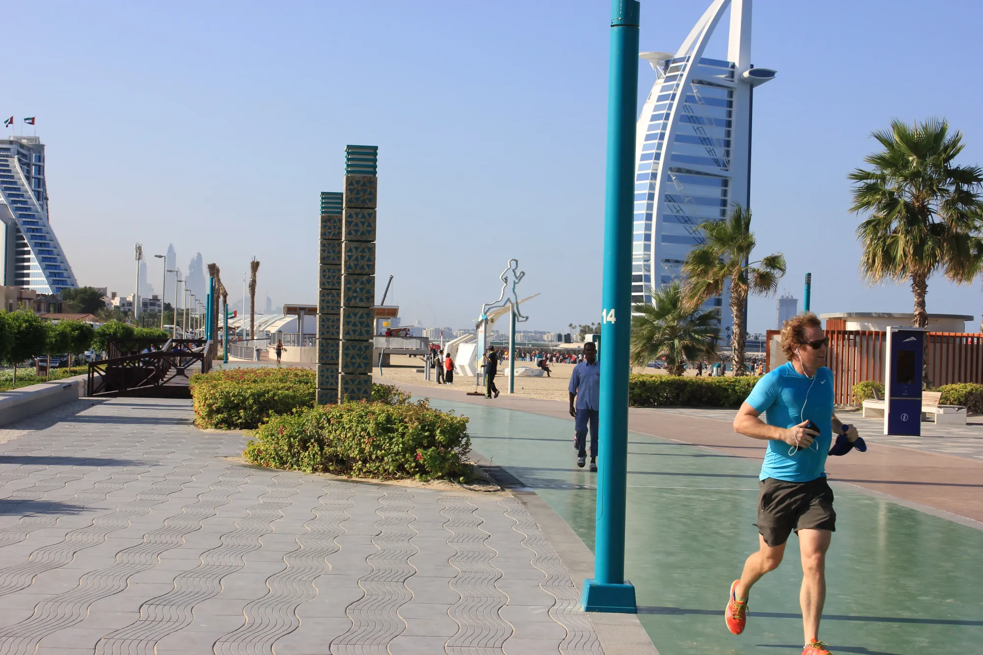 Jogger on Jumeirah Corniche walkway near Kite Beach with Burj Al Arab in the background