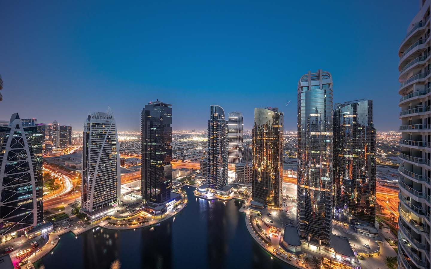 Night view of Dubai apartment towers with modern district cooling systems and illuminated skyline