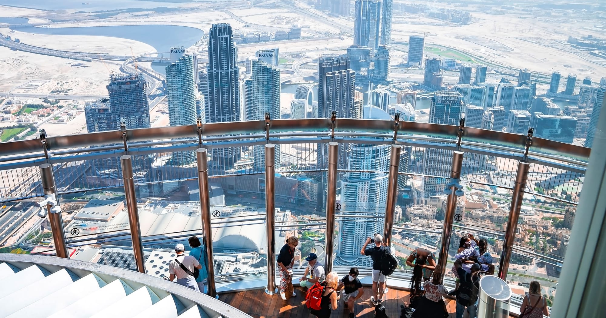 Tourists at Burj Khalifa observation deck overlooking Dubai skyline and city attractions