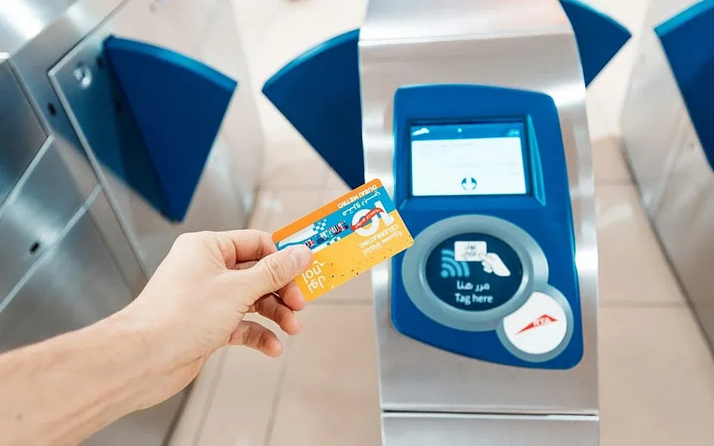 Commuter paying for Dubai Metro with RTA Nol card at station gate in 2025.