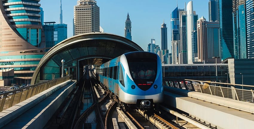 Dubai Metro train approaching Sobha Realty station with skyscrapers of Dubai Marina skyline in 2025