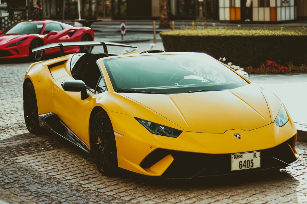Yellow Lamborghini Huracan EVO Spyder rental in Dubai with Ferrari in background