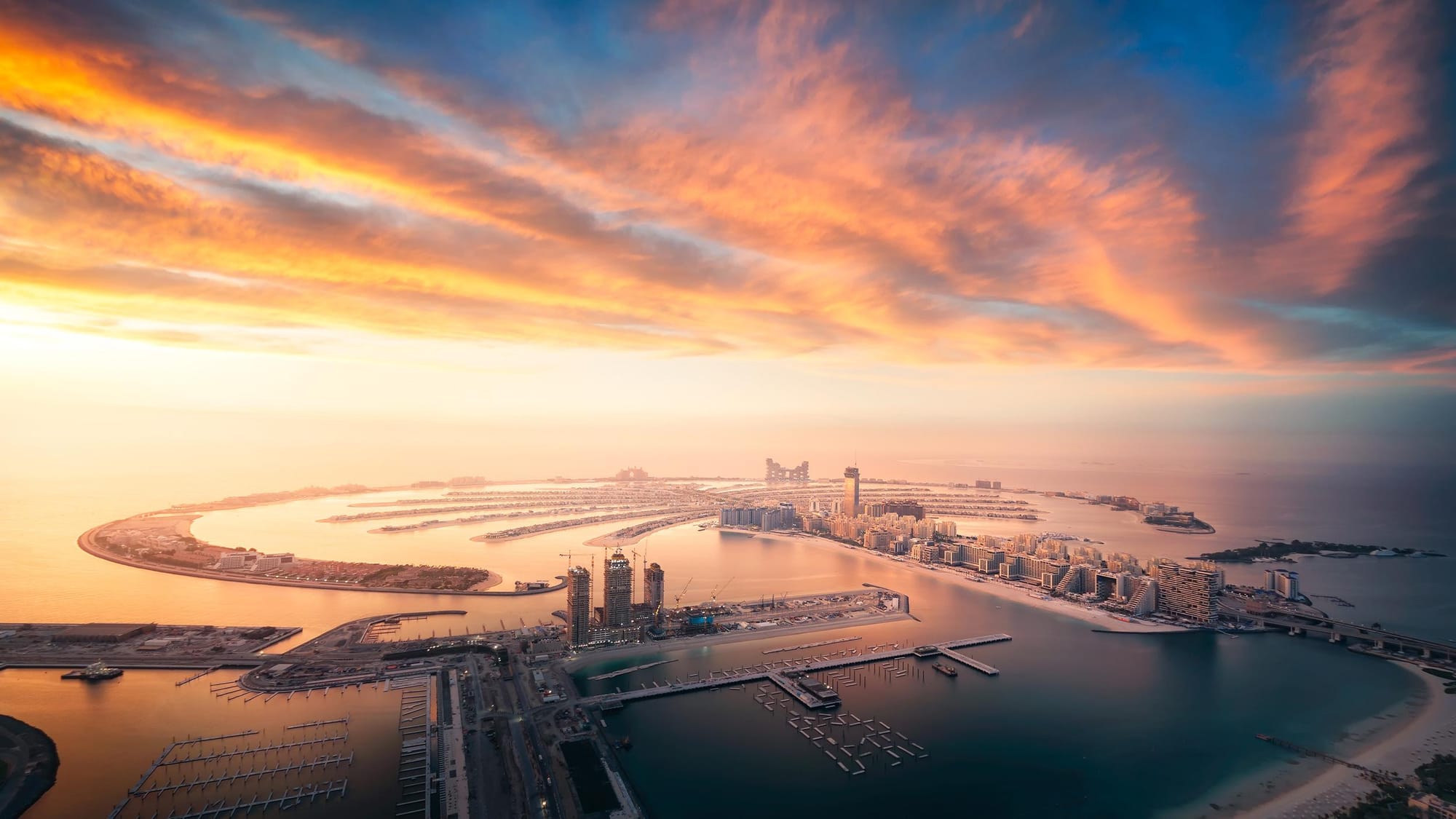 Aerial view of Palm Jumeirah Dubai at sunset with luxury hotels and skyline in the background