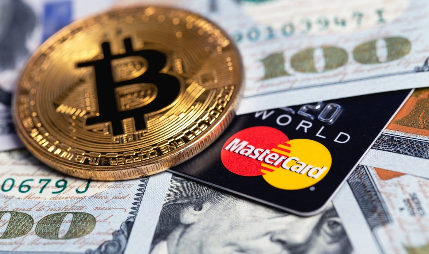 Bitcoin coin with Mastercard credit card and USD cash in background.