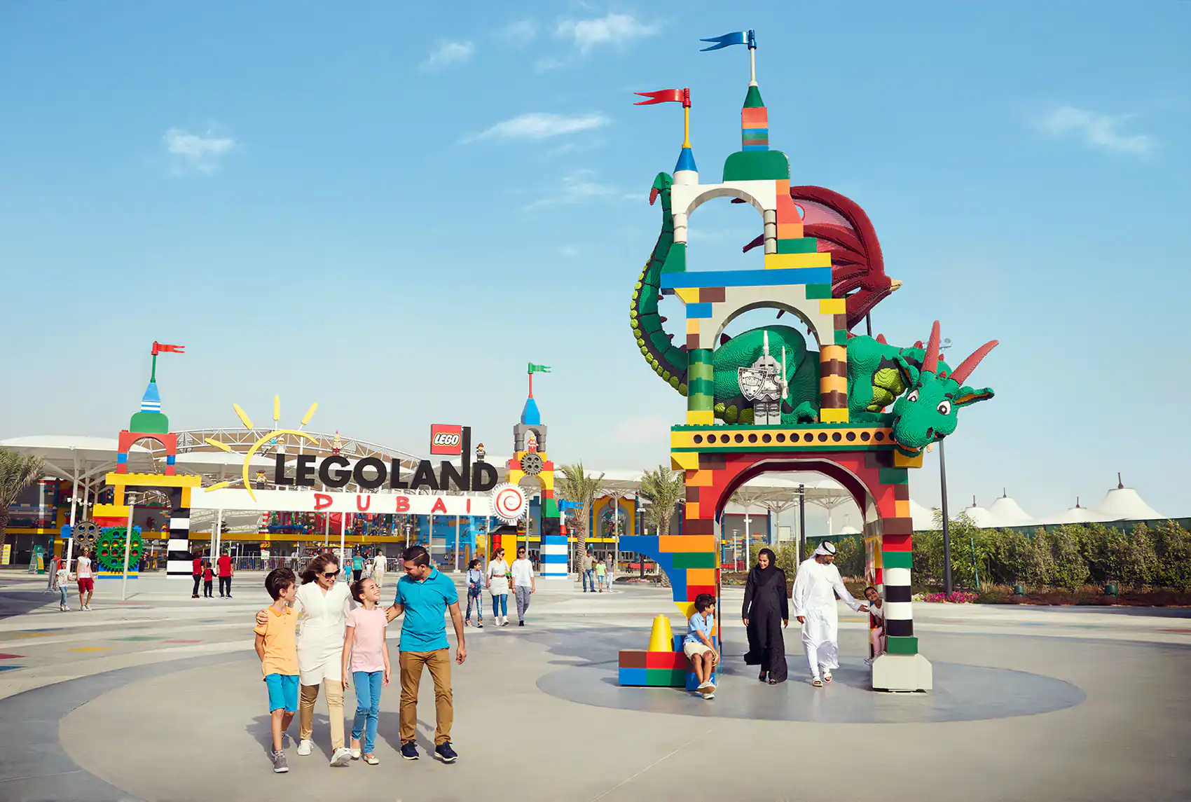 Families walking at the entrance of LEGOLAND Dubai with colorful LEGO structures and a dragon-themed archway.