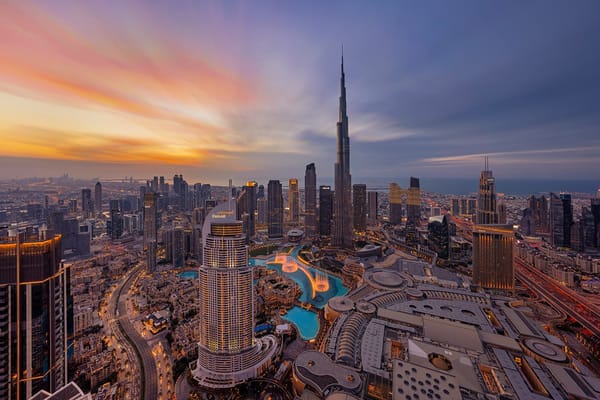 Aerial view of Downtown Dubai skyline with Burj Khalifa and Dubai Fountain at sunset.