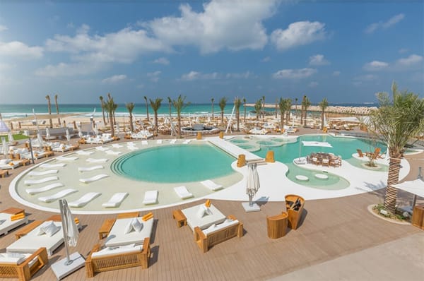 Luxury poolside setup with loungers and cabanas at Nikki Beach Dubai overlooking the sea at Pearl Jumeira