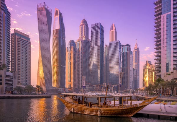 Dubai Marina waterfront at sunset with dhow boat and modern skyscrapers