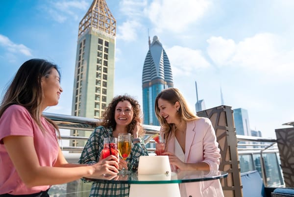 Tourists enjoying rooftop drinks with Dubai skyline views – highlighting travel insurance benefits in 2025