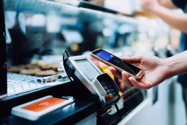 Tourist using smartphone for contactless card payment at a Dubai store in 2025.