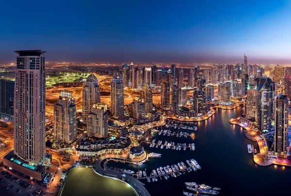 Dubai Marina skyline at night with yachts docked along the waterfront and illuminated skyscrapers in 2025